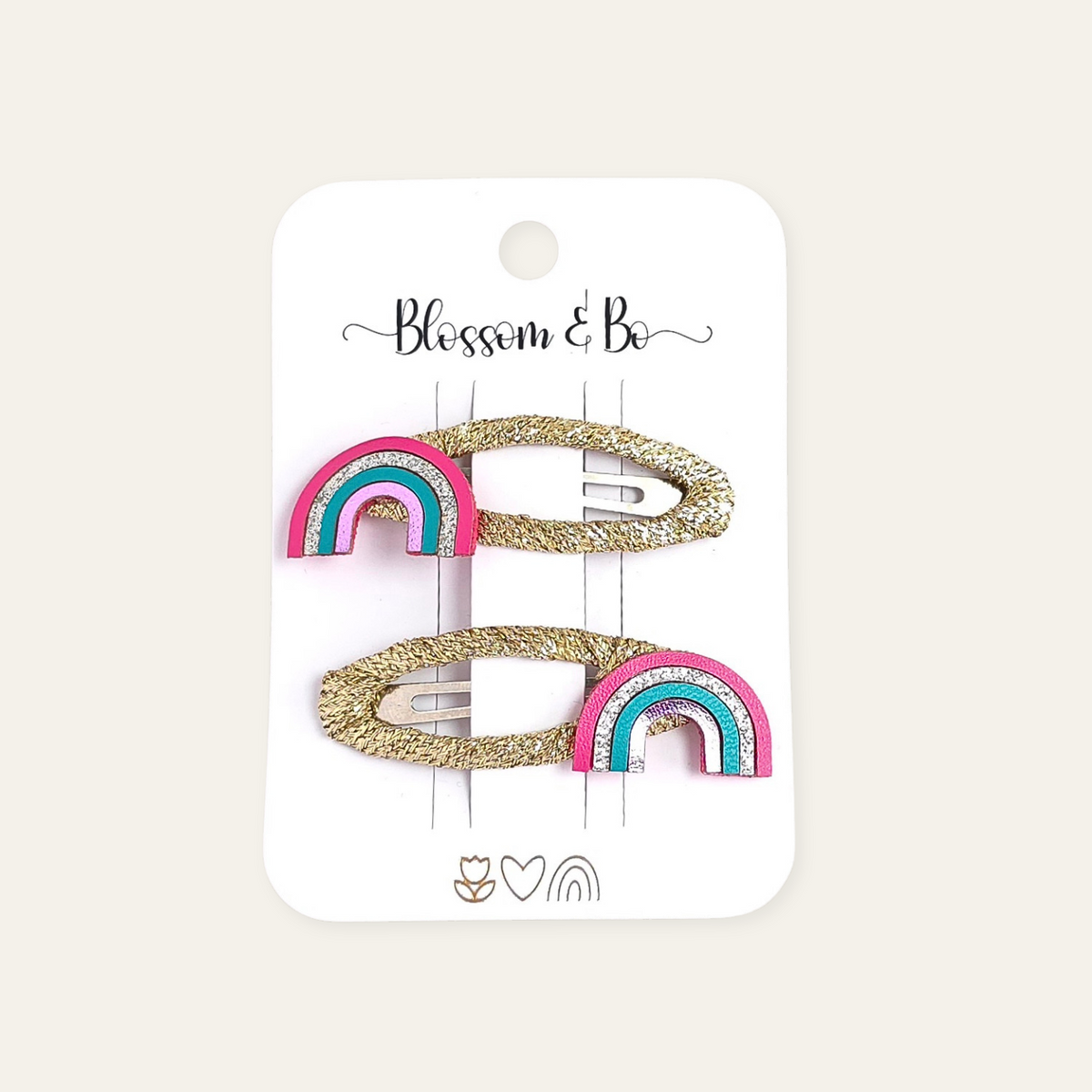 Two gold glitter hair snap clips with pink and turquoise rainbow accents, displayed on a white card labeled 'Blossom & Bo'.