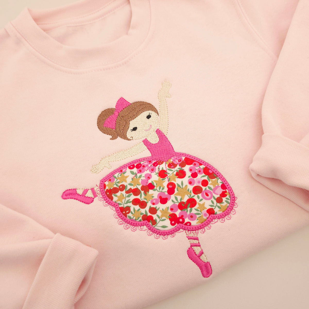 Close up of an embroidered ballerina with a pink floral Liberty of London fabric applique skirt