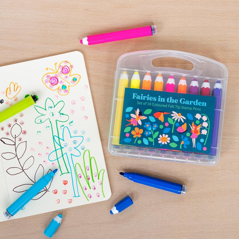 Set of 'Fairies in the Garden' colored felt tip stamp pens in a clear case on a wooden surface.