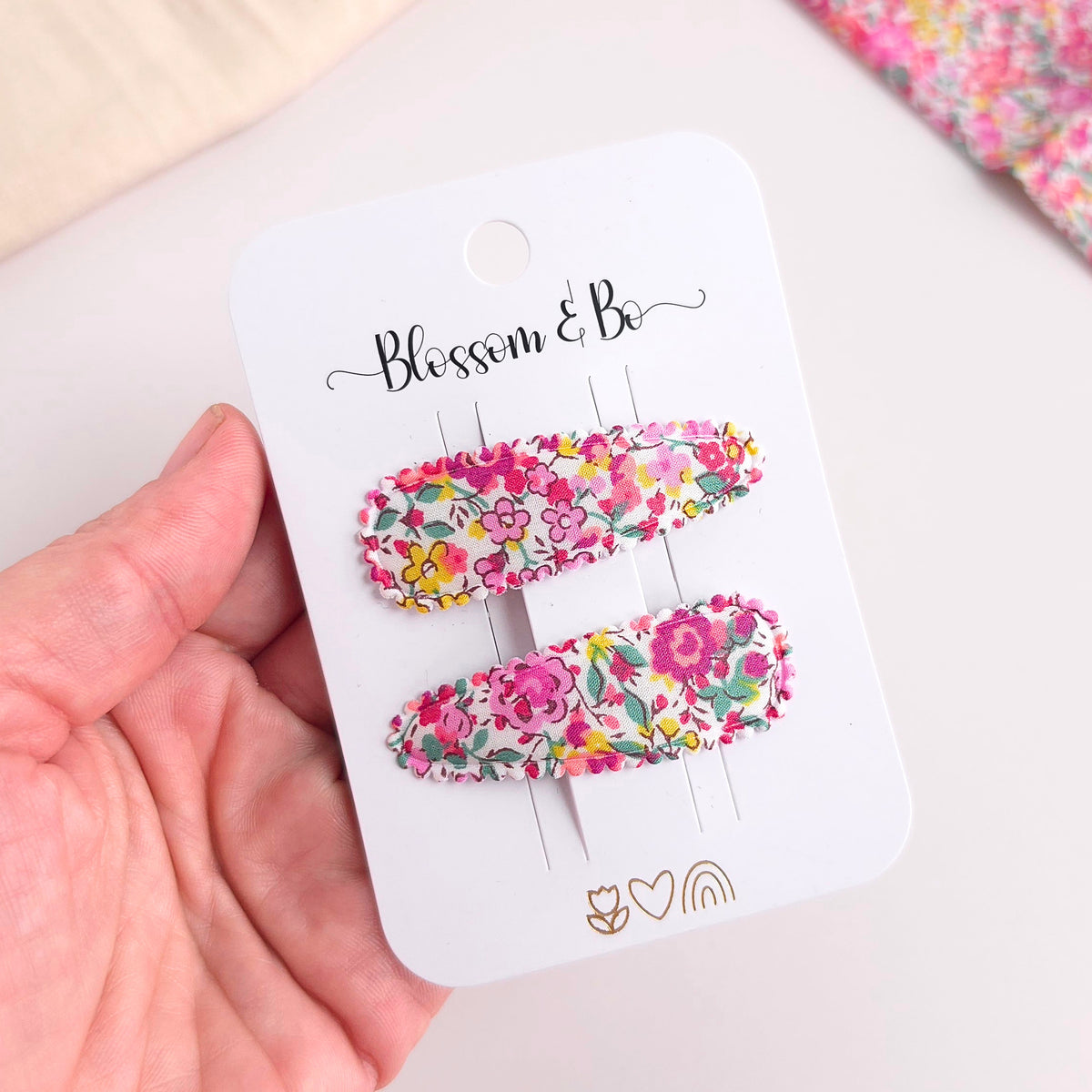 Floral hair clips on a 'Blossom & Co' branded card held by a hand.