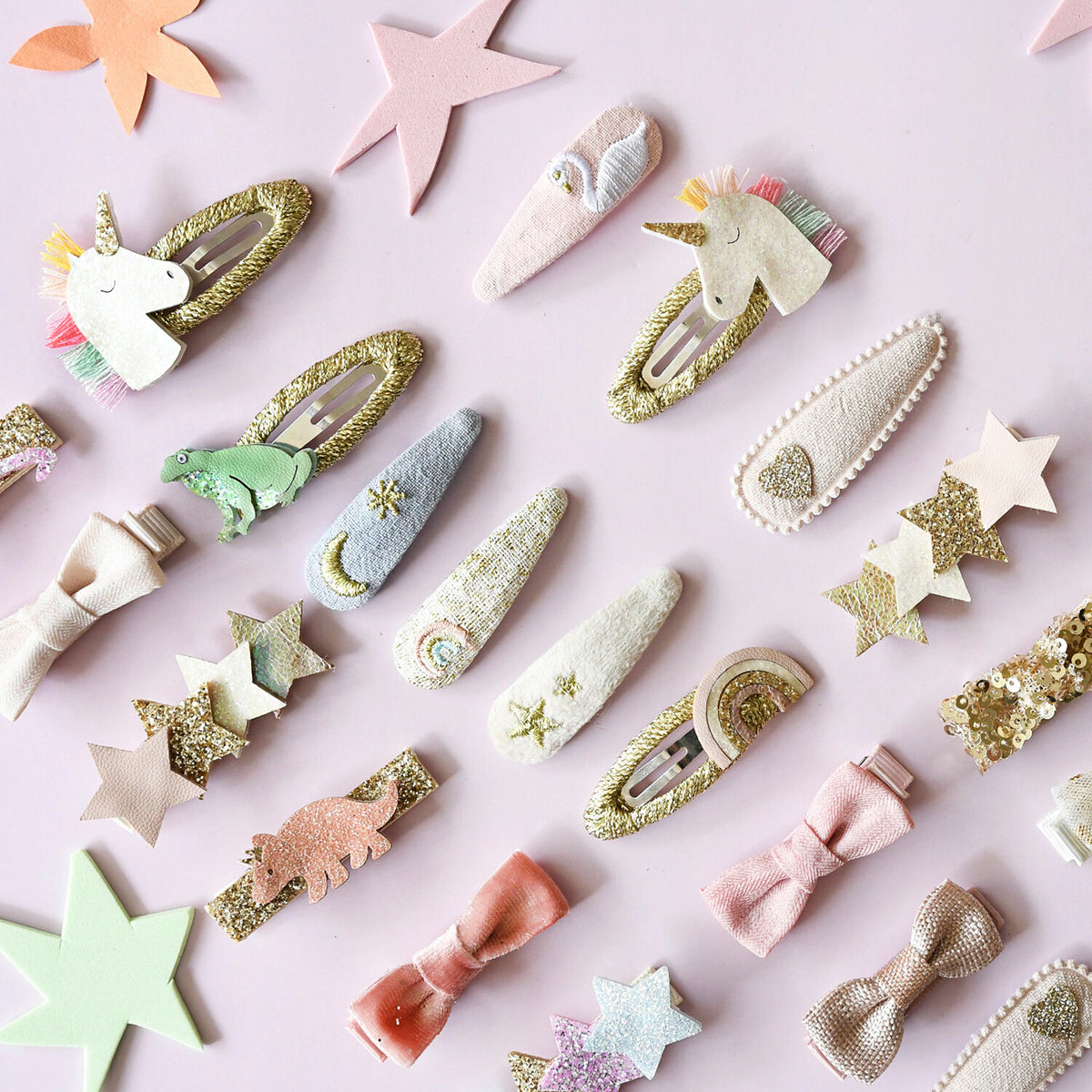 Collection of colorful hair clips and decorative stars on a light pink background