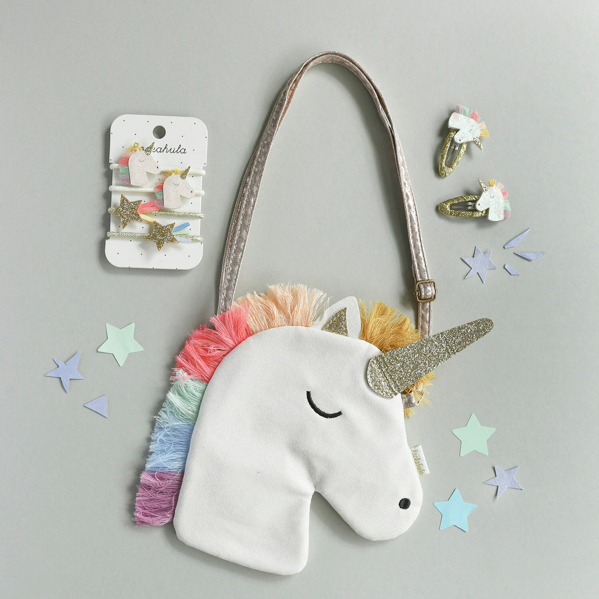 Unicorn-shaped bag with rainbow hair and gold horn on a gray background