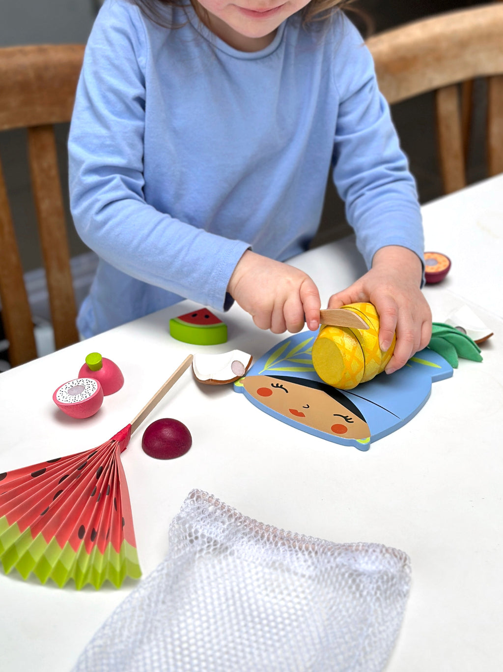 Child playing with toy wooden fruits and a bag on a table