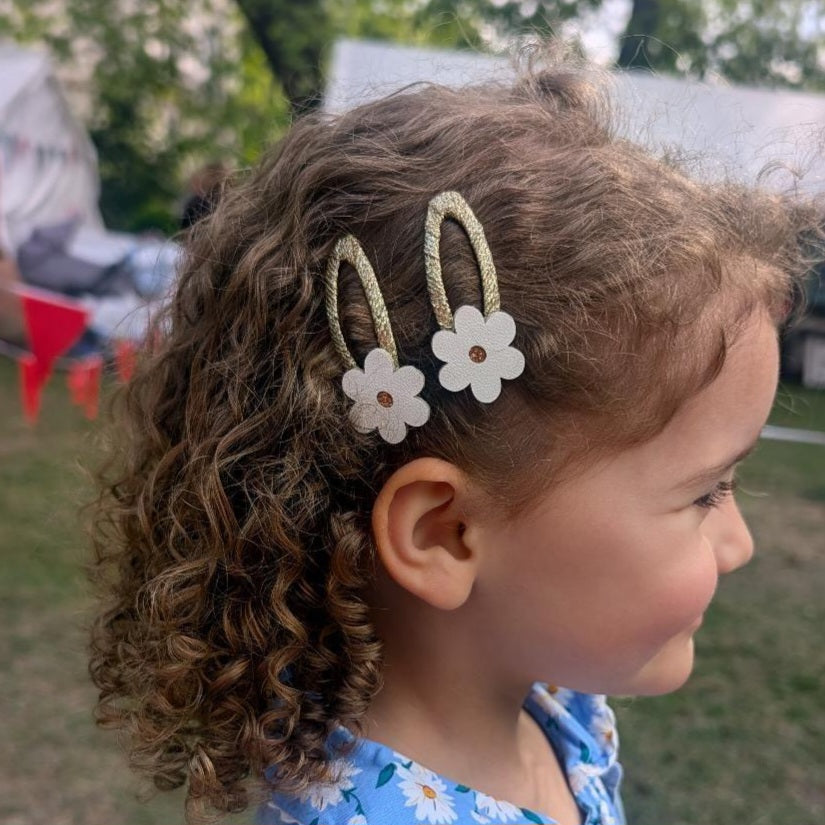 Daisy flower hair clips for girls shown in curly hair