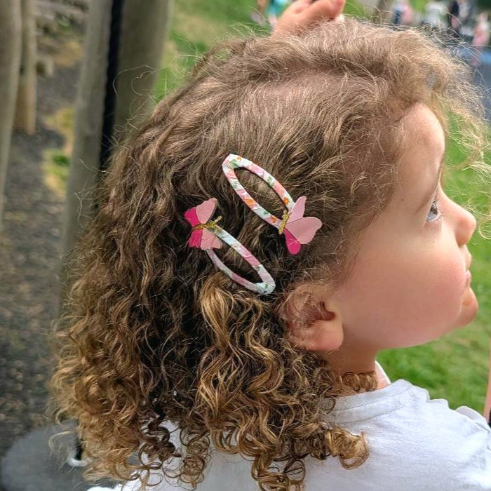 Butterfly hair clips for girls shown in curly hair with pink butterfly details