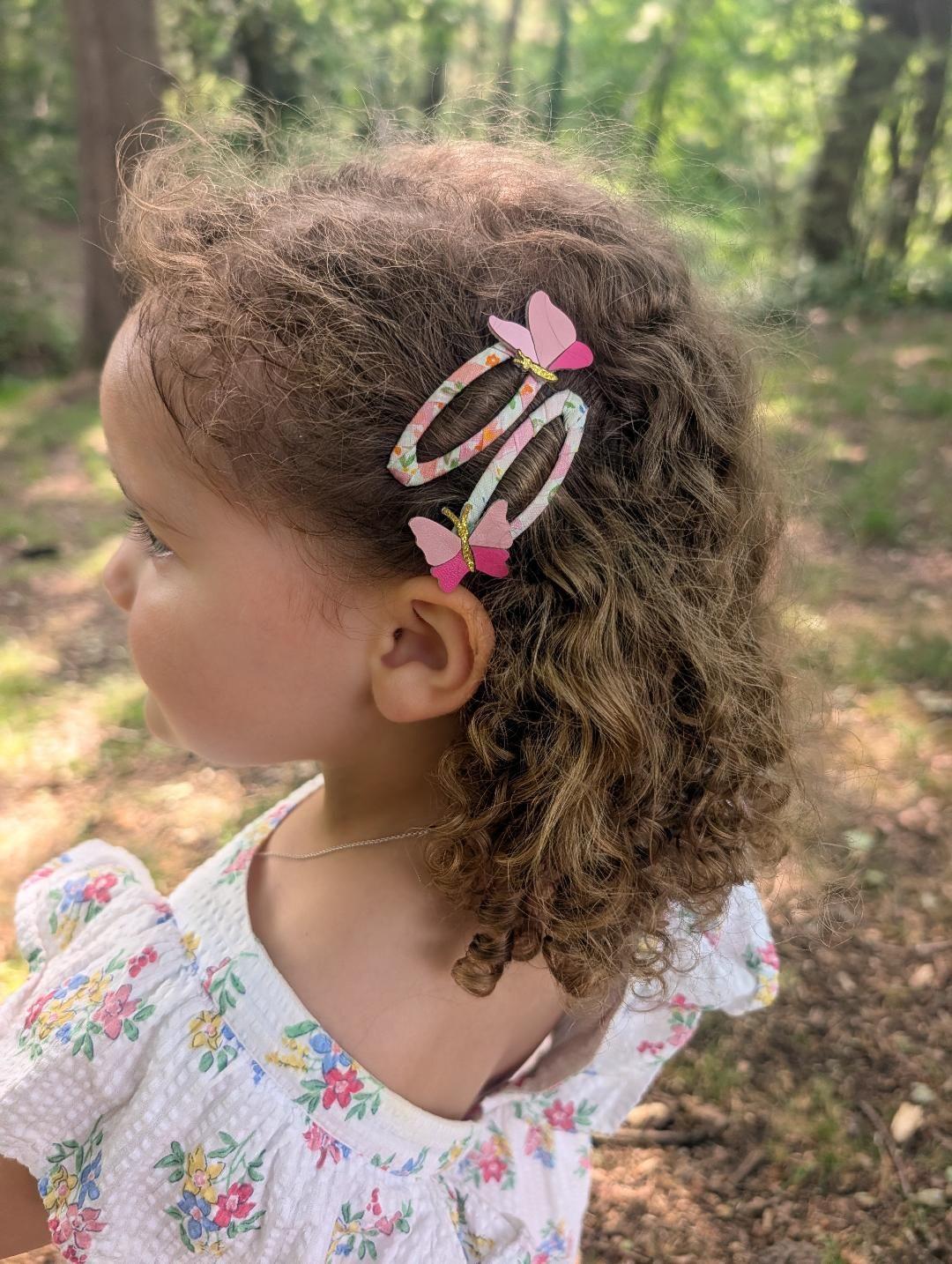 Butterfly hair clips for children shown in curly hair with floral fabric snap clips
