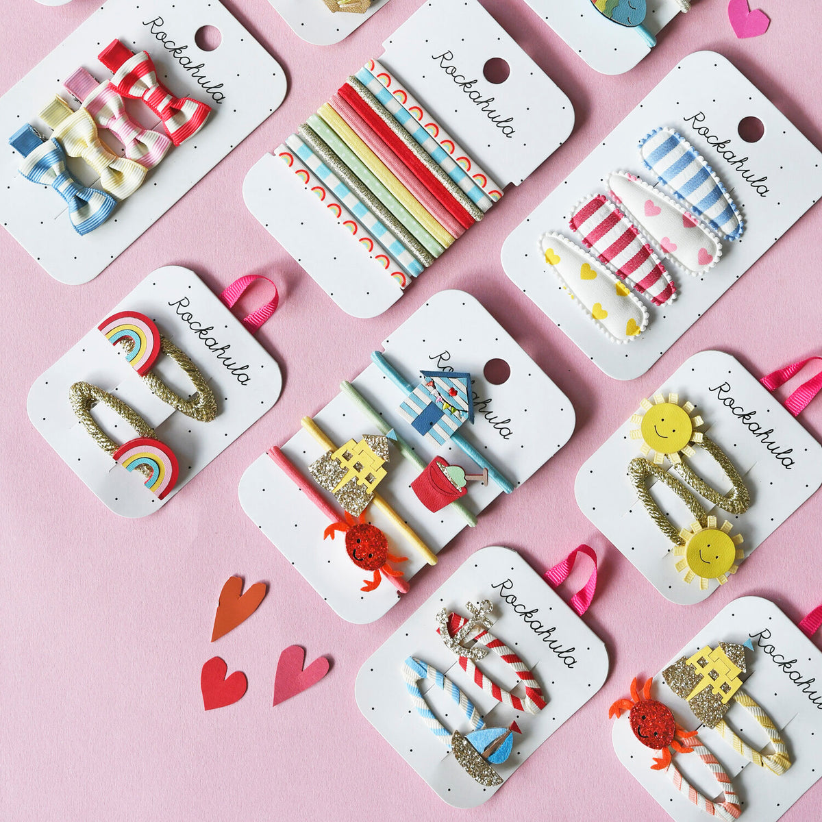 Colorful Rockahula hair accessories on display cards with a pink background