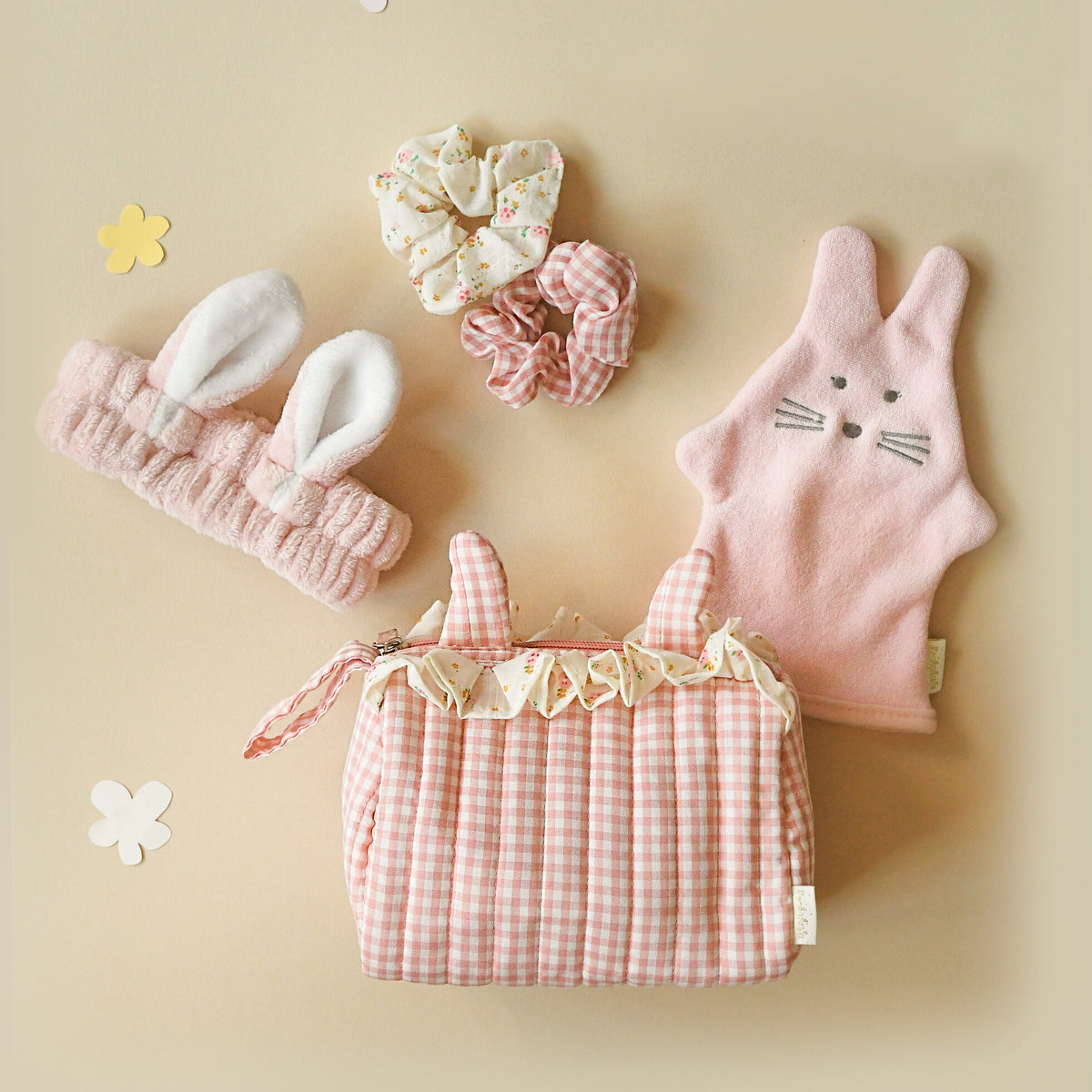 Set of pink bunny-themed hair accessories including headbands and a pouch on a beige background.