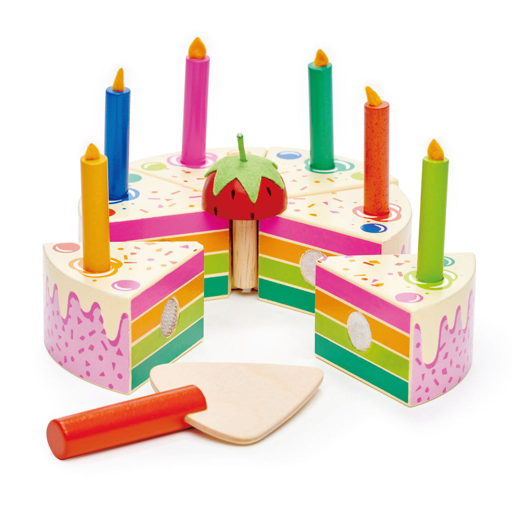 Colorful wooden cake toy with different coloured candles, a strawberry in the centre and a wooden knife on a white background