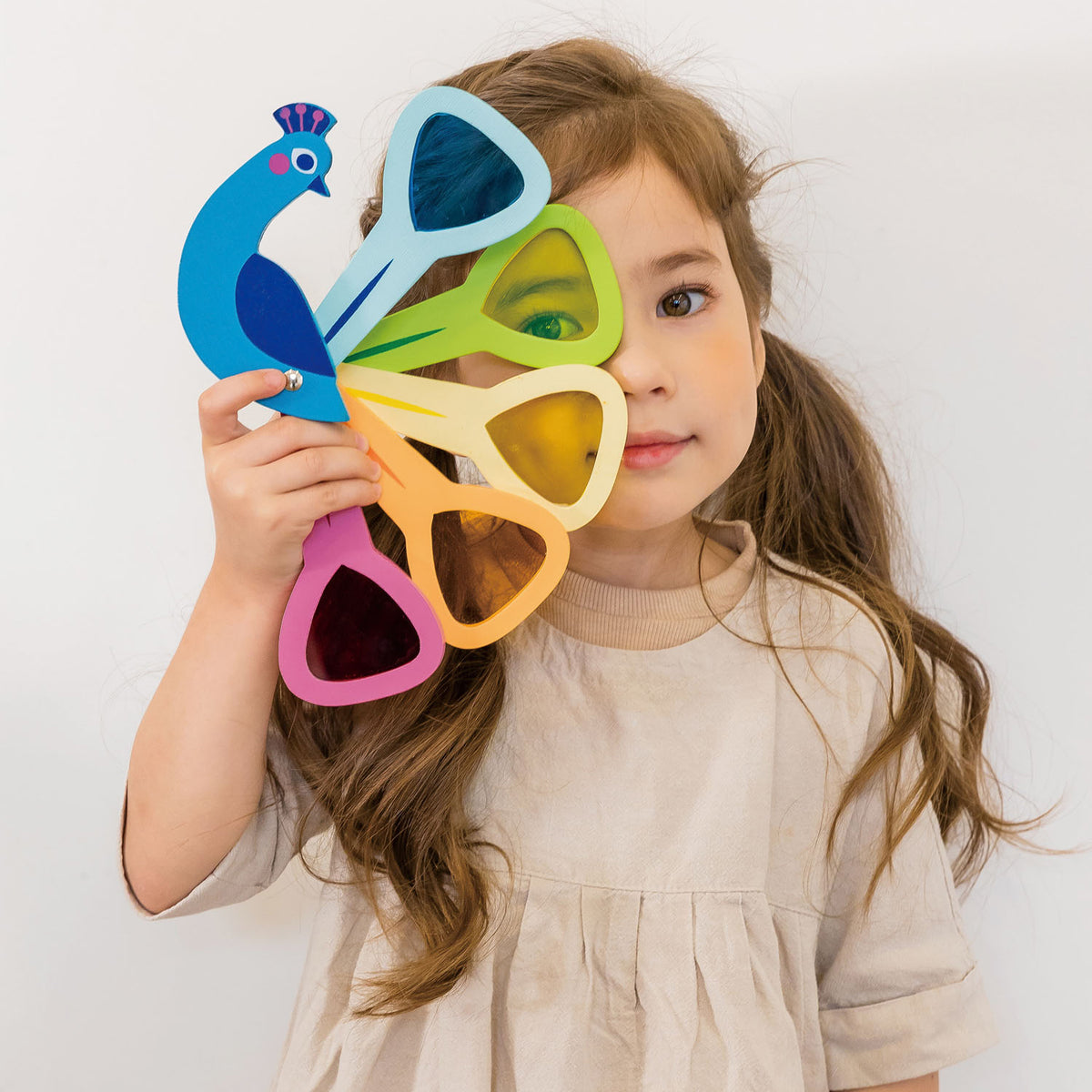 A child looking through a Tender Leaf wooden peacock with coloured acrylic feathers.