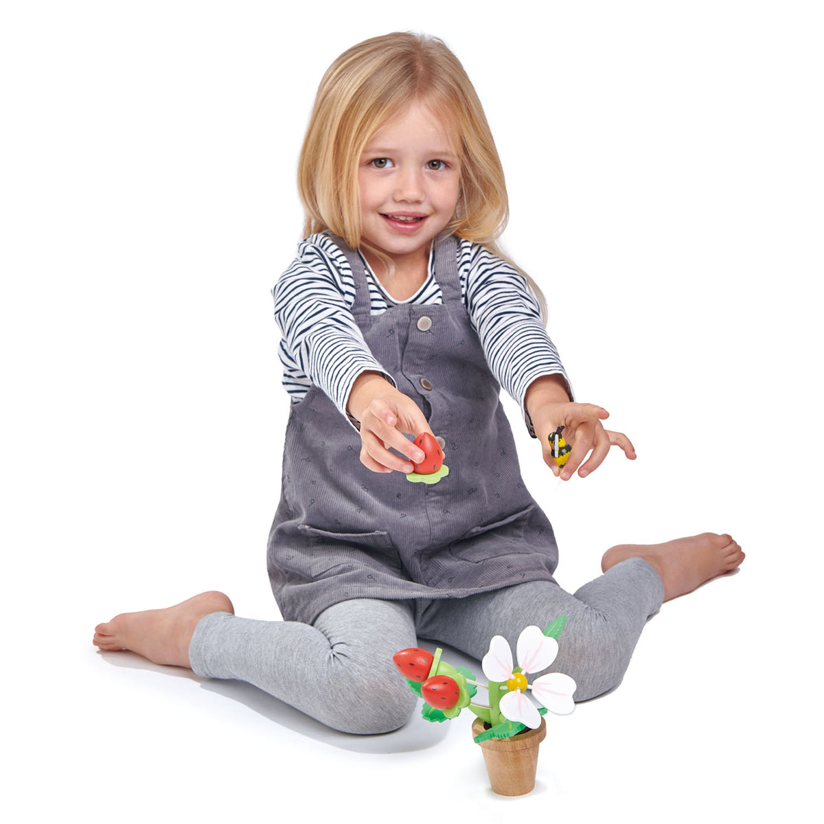 Child playing with strawberry plant wooden toy 
