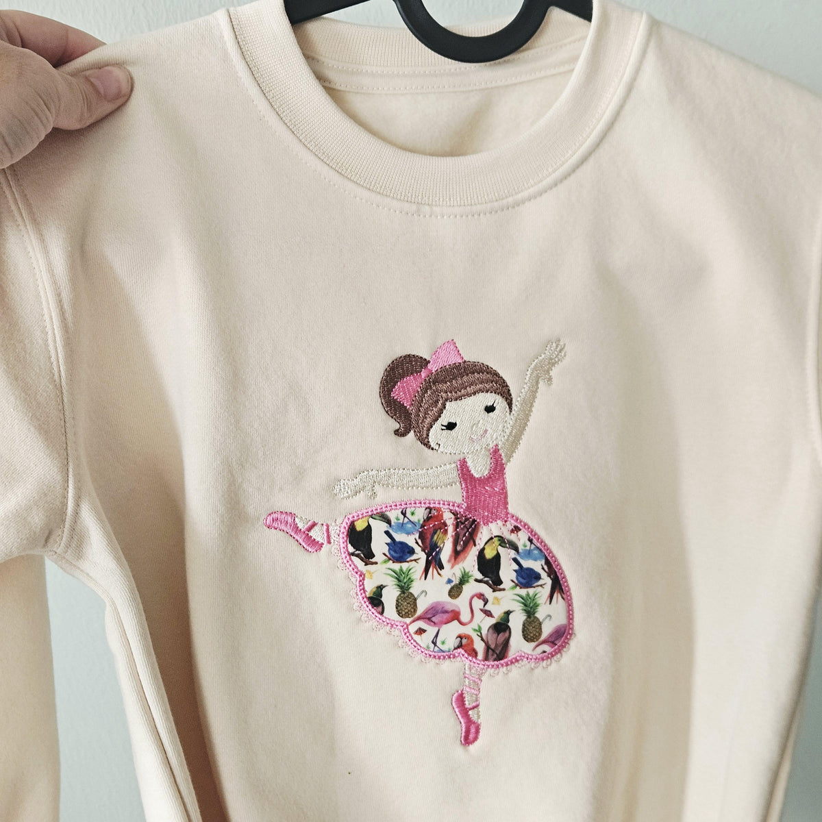 Beige sweatshirt with a ballerina design on a hanger