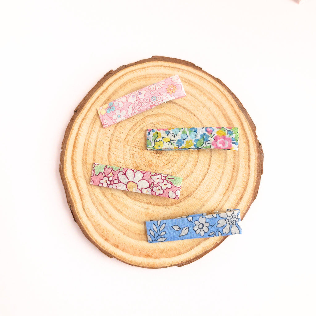 Floral-patterned hair clips on a wooden surface