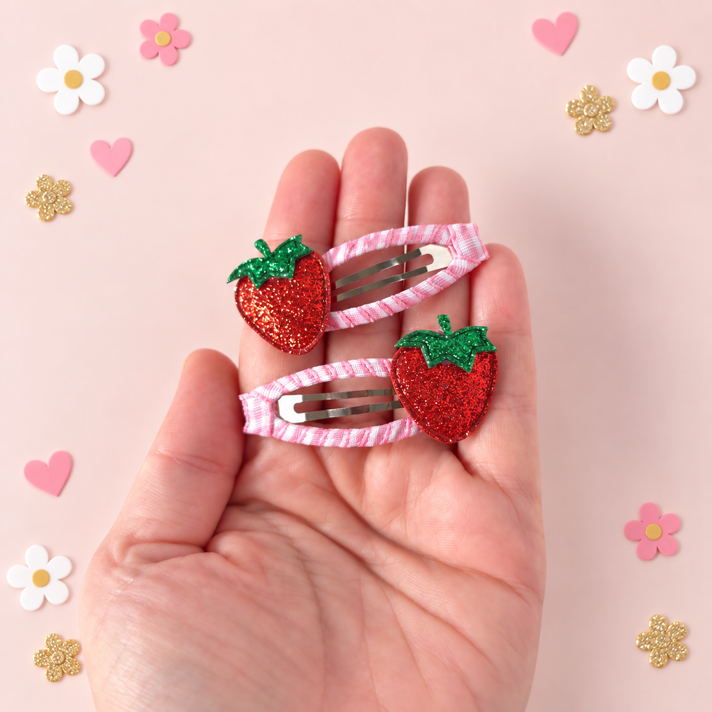 Strawberry hair clips for girls shown in hand with pink gingham ribbon