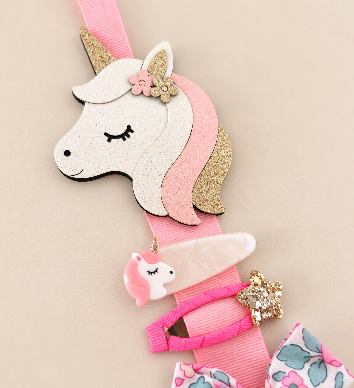 Unicorn hair clip holder displaying unicorn and colourful girls' hair clips with pink ribbon