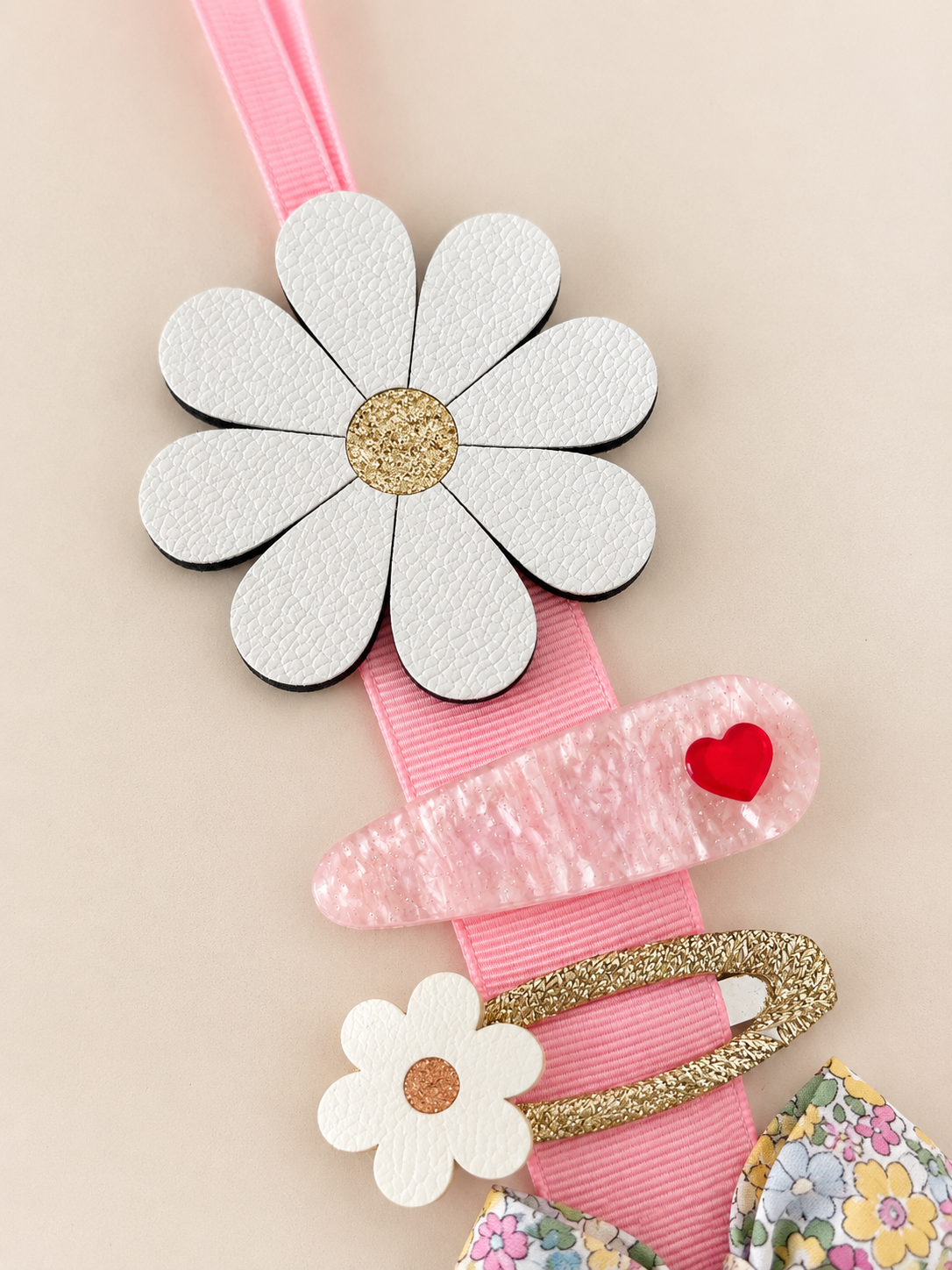 White faux leather daisy hair clip holder with pink ribbon displacing two hair clips