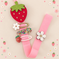 Strawberry hair clip holder with pink ribbon displaying girl's hair clips