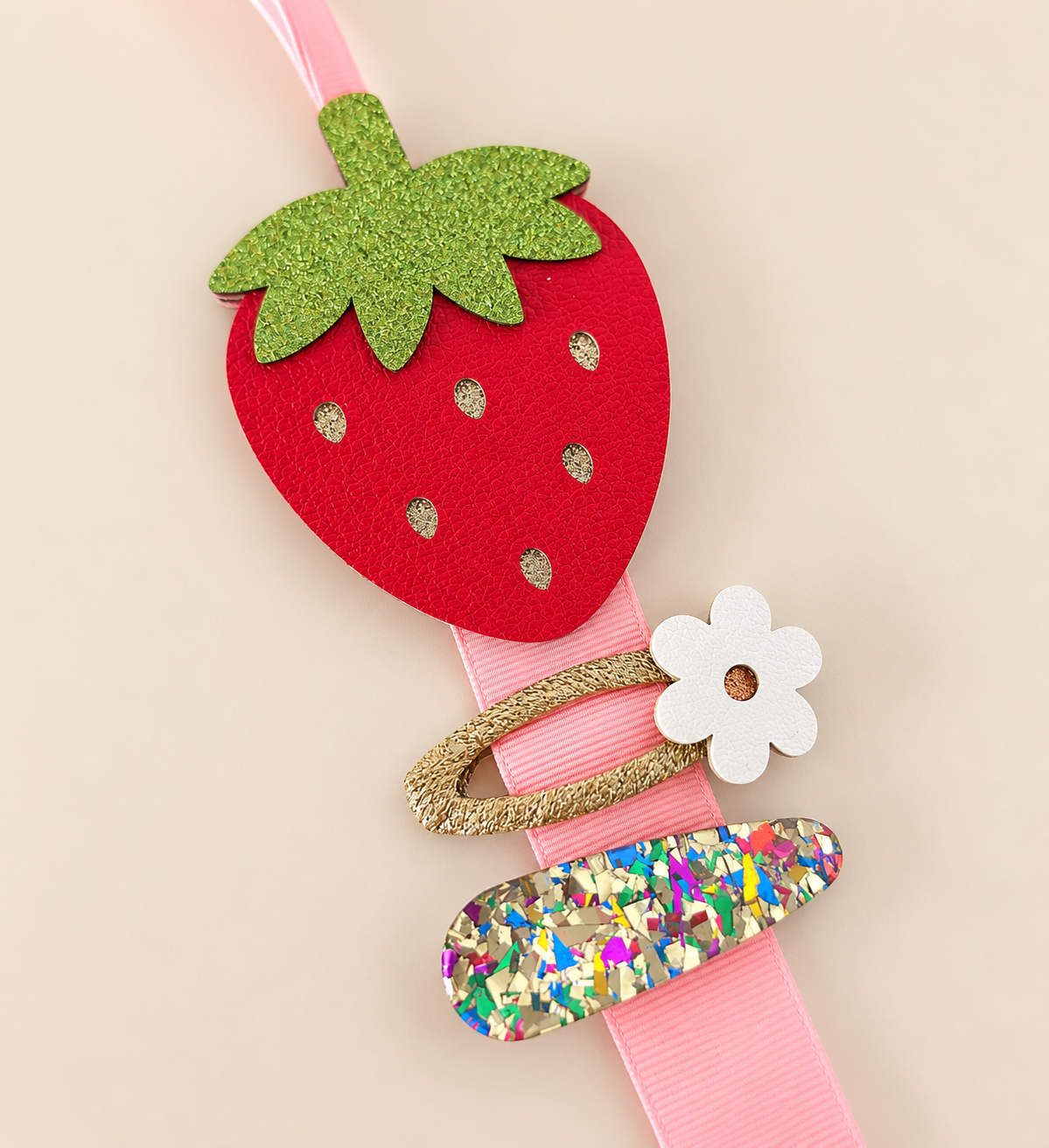 Strawberry hair clip holder displaying flower and colourful hair clips on pink ribbon